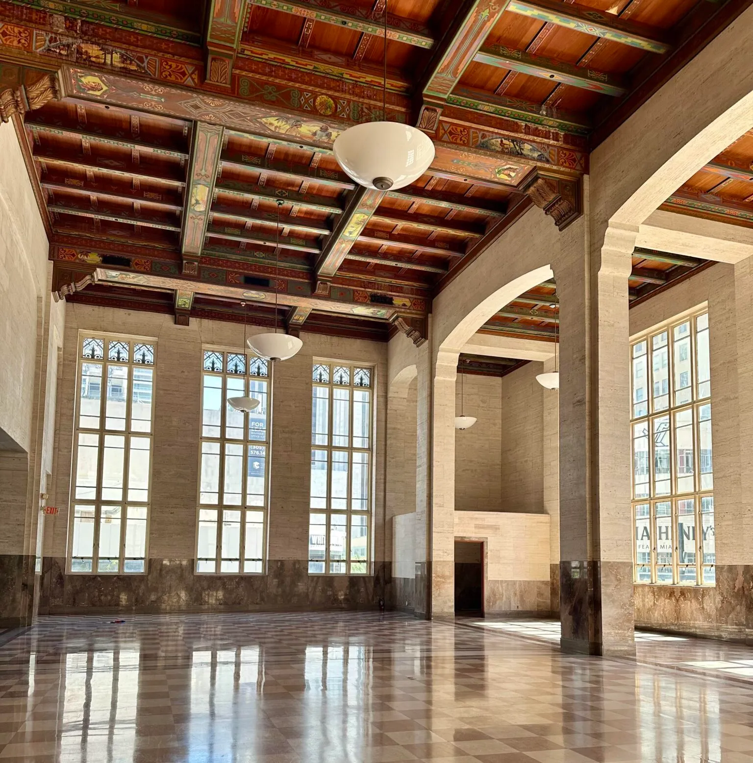 The banking hall: painted wood ceiling, tall windows, checkered marble floor